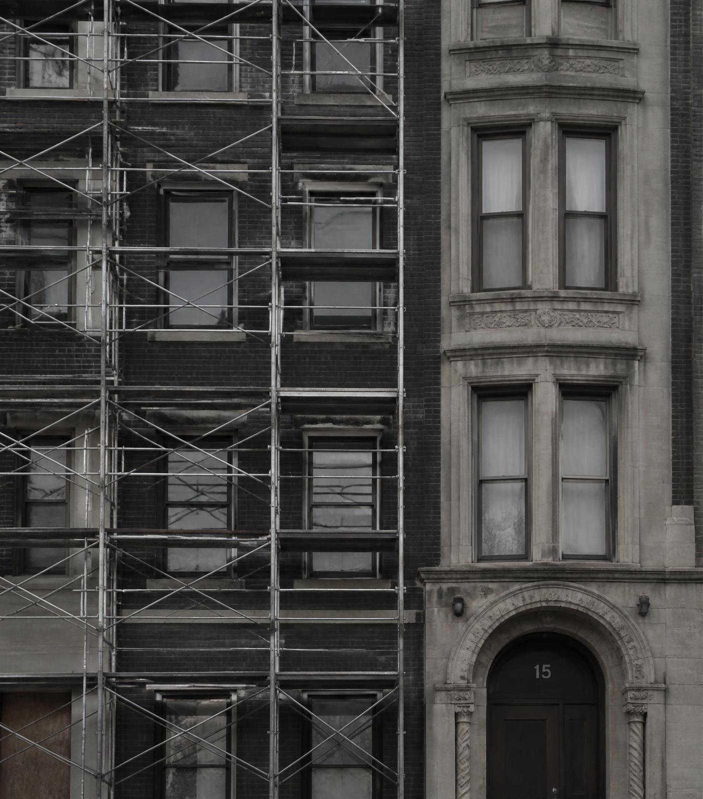 Brick and stone multifamily building facade under renovation with scaffolding